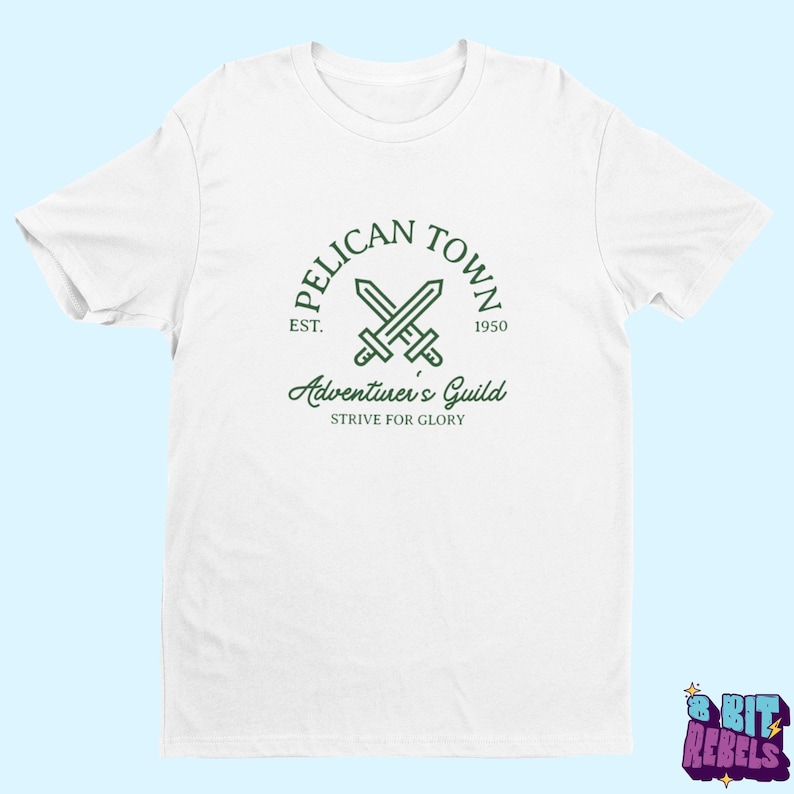 K&ouml;nnte beinhalten: Wei&szlig;es T-Shirt mit einem gr&uuml;nen Aufdruck. Das Design zeigt die Worte "PELICAN TOWN", gekreuzte Schwerter und "Adventurer's Guild". Das T-Shirt hat auch den Text "EST. 1950" und "STRIVE FOR GLORY".