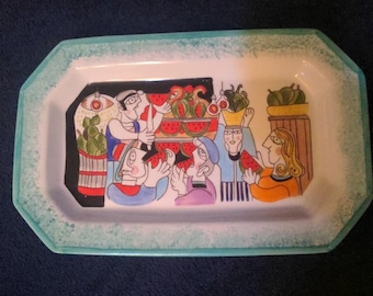 May include: A rectangular ceramic serving tray with a white center and a light blue mottled border. The center features a colorful illustration of people eating watermelon slices, with baskets of fruit and stylized figures in a market setting.
