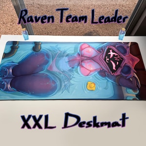 Puede incluir: Alfombrilla de escritorio XXL con un personaje estilizado en tonos azules y rosas. La alfombrilla tiene el texto "Raven Team Leader" y "XXL Deskmat" en morado. Un pequeño patito de goma amarillo está en la imagen.