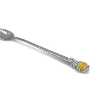 Peut inclure: Une cuillère à mélanger en argent avec une perle de verre jaune sur le manche.