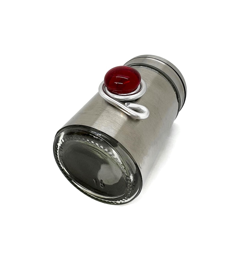 May include: A silver metal spice jar with a red glass knob on the lid.