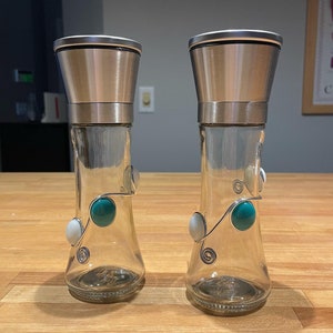 May include: Two silver and glass salt and pepper shakers with a decorative wire design and turquoise and white beads.