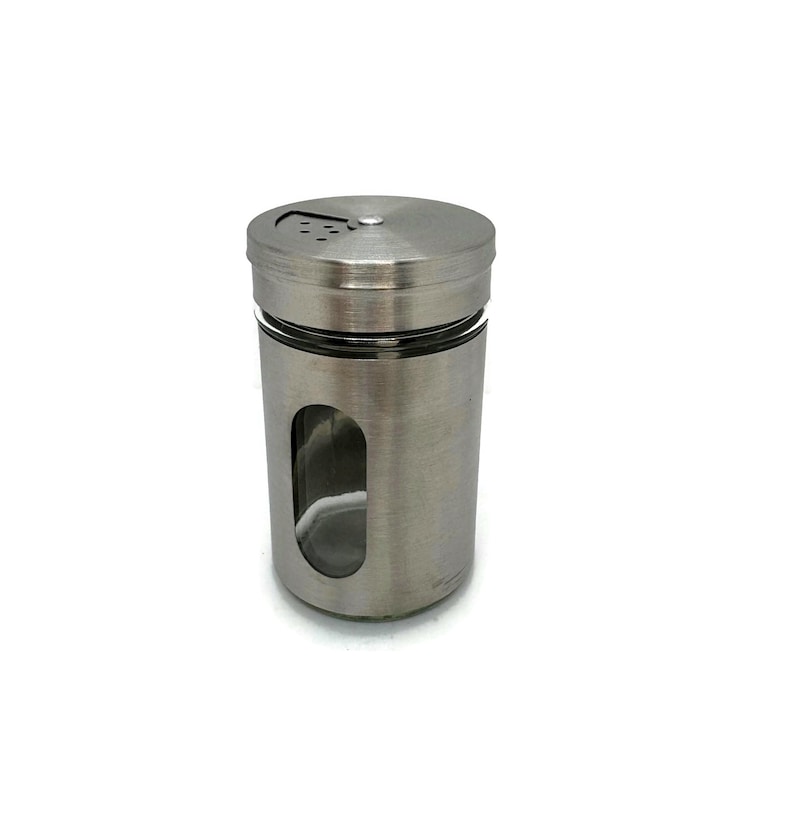 May include: A stainless steel spice shaker with a clear glass window to view the contents. The shaker has a twist-top lid with holes for dispensing spices.