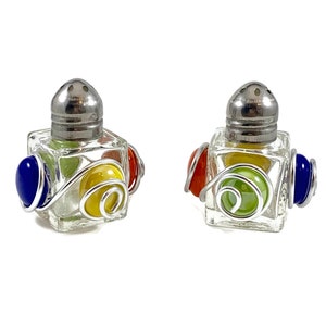 May include: A set of two glass salt and pepper shakers with silver tops and colourful glass accents. The shakers are decorated with silver wire and have a unique design.