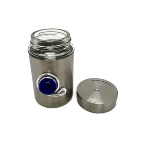 May include: A silver spice jar with a blue glass eye charm. The jar has a clear glass top and a silver lid.