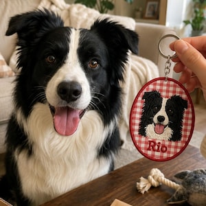 May include: An oval-shaped keychain featuring an embroidered portrait of a black and white Border Collie dog on a red and white gingham background. The name Rio is stitched in red thread below the dog. The keychain has a silver metal ring.