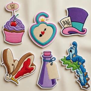 May include: Embroidered patches featuring characters and objects from Alice in Wonderland. Includes a cupcake with "Eat Me" text, a heart-shaped lock, a Mad Hatter hat, a butterfly, a potion bottle, and a blue caterpillar.
