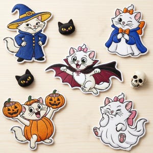 May include: A collection of embroidered patches featuring white kittens in various costumes, including a witch, a vampire, and a pumpkin, alongside two small black cat head patches and a miniature skull figurine.