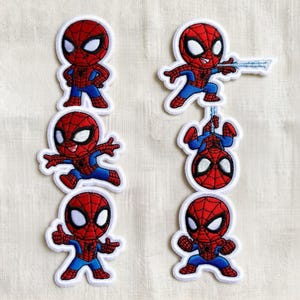 May include: Six embroidered patches featuring a cartoon character in a red and blue suit with a spider web pattern. The character is shown in various poses including standing, jumping, shooting a web, hanging upside down, and giving a thumbs up.