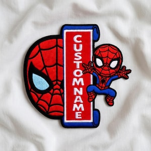 May include: Embroidered patch featuring Spider-Man elements. The design includes a red and black Spider-Man mask, a red rectangle with the text "CUSTOM NAME", and a small Spider-Man figure in a jumping pose. The patch has a blue border.