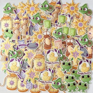 May include: A collection of embroidered patches featuring a variety of designs. The patches include images of a yellow sun, a green chameleon, a yellow duck, lanterns, and flowers. The text "Snuggly Duckling" is visible on some patches. The color palette includes yellow, green, purple, and tan.