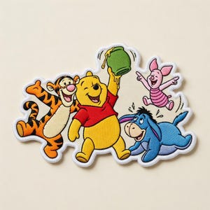 May include: Embroidered patch featuring Winnie the Pooh, Tigger, Piglet, and Eeyore. Winnie the Pooh is holding a green honey pot. Tigger is orange and black. Piglet is pink. Eeyore is blue. The patch has a white border.