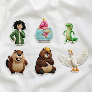 May include: A collection of embroidered patches featuring cartoon characters. Includes a person in a green jacket, a fish in a bowl, a green lizard, a beaver, a bear with a crown, and a goose with outstretched wings.