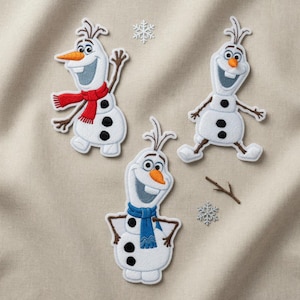 May include: Three embroidered patches of Olaf the snowman from Frozen. Olaf has a carrot nose, twig arms, and black button eyes. One Olaf wears a red scarf, another a blue scarf. Two snowflake patches and a twig are also present.