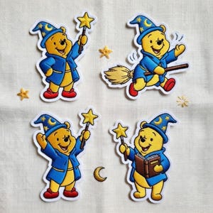 May include: Four embroidered patches featuring a yellow bear wearing a blue wizard outfit and hat. The bear is holding a star-shaped wand, a book, or riding a broom. Additional star and crescent moon patches are also included.