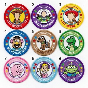 May include: A collection of nine circular embroidered patches featuring characters from the animated film series. Each patch has a character's image and name, including Woody, Buzz Lightyear, Jessie, Mr. Potato Head, Slinky Dog, Rex, Hamm, Bo Peep, and Alien.