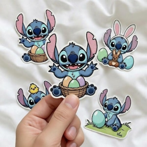 K&ouml;nnte beinhalten: Eine Sammlung von Stitch-Charakter-Patches in verschiedenen Ostermotiven. Die Patches zeigen Stitch mit Ostereiern, einem K&uuml;ken und Hasenohren. Die Patches sind blau, rosa und braun, mit einem wei&szlig;en Rand.