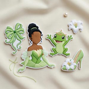 May include: Embroidered patches featuring a princess in a green dress, a green bow, a frog with a crown, a white flower, and a green high heel shoe. The patches are in shades of green, white, and brown, with detailed stitching.