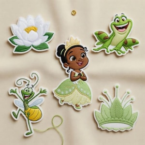 May include: Embroidered patches featuring a white water lily, a green frog, a cartoon princess in a green dress, a green insect, and a green crown. The patches are on a light beige fabric.