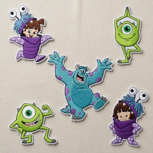 May include: Embroidered patches of characters from "Monsters, Inc.", including Mike Wazowski, James P. Sullivan, and Boo in her monster costume. The patches are in various poses and colours, including green, blue, and purple.