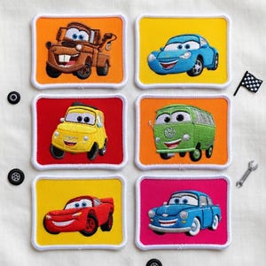May include: Embroidered patches featuring cartoon cars in various colors, including orange, yellow, red, green, and blue. Each patch has a white border and a different car design. Accessories like a wrench, a checkered flag, and wheels are also present.