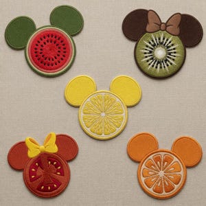 Puede incluir: Colección de cinco parches bordados con forma de cabezas de Mickey Mouse, cada uno diseñado para parecerse a una fruta diferente. Las frutas incluyen sandía, kiwi, limón, tomate y naranja. Los parches son coloridos y detallados.