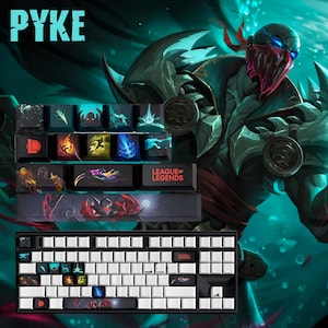 Può includere: Una tastiera meccanica con tasti bianchi e tasti personalizzati con opere d'arte di League of Legends. I tasti mostrano vari disegni di personaggi e il logo del gioco. La parola "PYKE" è in alto a sinistra.