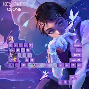 May include: Purple keycaps with character art and the text "KEY CAPS CLONE". The keycaps feature a design inspired by the game Valorant. The image has a purple and blue colour scheme, with the word "VALORANT" visible.
