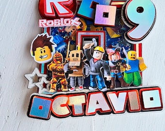 May include: A vibrant Roblox cake topper with the Roblox logo, the number 9, and character cutouts. The name "OCTAVIO" is displayed in large, holographic letters. The design incorporates red, blue, and silver accents, suitable for a birthday celebration.
