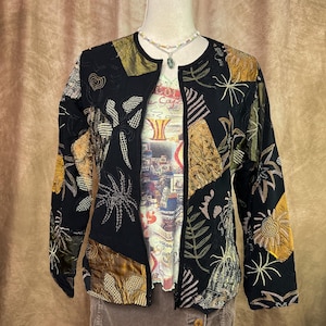 May include: A white ceramic mug with a black handle and the text "But First, Coffee" in a black, bold font. The mug is sitting on a wooden surface. The mug is approximately 4 inches tall.