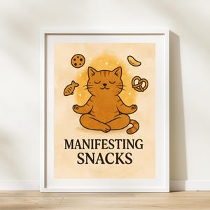 Peut inclure: Impression encadrée avec un chat de dessin animé méditant, avec le texte « Manifesting Snacks ». Le chat orange est en position du lotus, entouré d'illustrations de collations, dont un biscuit, un poisson et un bretzel. Le fond est orange clair avec des étoiles.