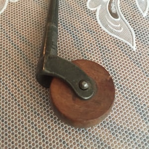 May include: A close-up of a wooden caster wheel with a metal swivel arm. The wheel is brown and the arm is silver.