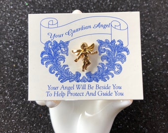 Pode incluir: Um alfinete de anjo dourado em um cartão branco com letras azuis que dizem "Your Guardian Angel" e "Your Angel Will Be Beside You To Help Protect And Guide You".