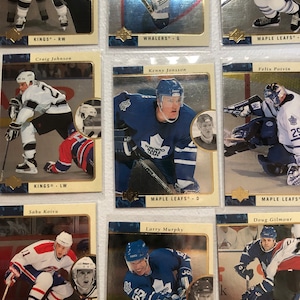 May include: A collection of nine hockey trading cards featuring NHL players. The cards are silver with gold accents and feature photos of the players in their hockey uniforms. The cards include players from the Kings, Whalers, and Maple Leafs.