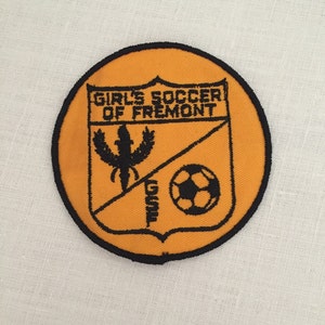 May include: Orange and black embroidered patch with the text "Girl's Soccer of Fremont" and a soccer ball.