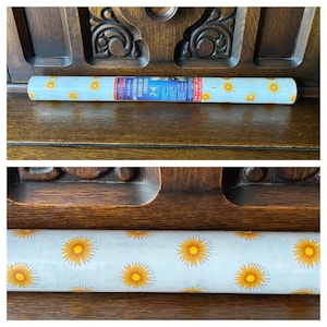 May include: A roll of light blue contact paper with a repeating pattern of yellow and orange sunflowers. The paper is labeled "Contact" and "Self-Adhesive Multipurpose Decorative Liner". The roll is approximately 18 inches wide and 24 feet long.