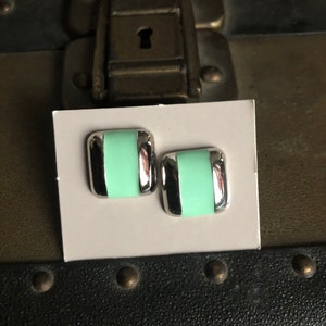 May include: A pair of silver and mint green square earrings. The earrings have a silver border and a mint green center.