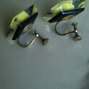 May include: A pair of yellow and black geometric clip-on earrings with gold metal backs.