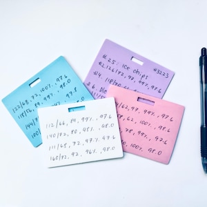 May include: Four colorful rectangular cards with handwritten numbers and a black pen on a white background. The cards are blue, pink, purple, and white. The purple card has the text "Ice chips".