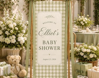 May include: A vertical welcome sign for a baby shower featuring a sage green and white gingham pattern, sage green ribbons tied at the top corners, and text that reads Welcome to Elliot's Baby Shower August 23, 2026, displayed on a wooden frame.
