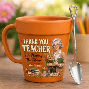 May include: An orange terracotta-style ceramic mug with a handle, featuring the text THANK YOU TEACHER For Helping Us Bloom and Mrs. Eleanor. The design includes an illustration of a teacher holding flowers, books, and an apple. A silver spoon is included.