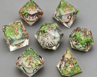 May include: A set of seven polyhedral dice for tabletop games. Each die is made of clear resin, with green plant inclusions and copper-coloured numbering. The dice are various shapes, including a d20, d12, d10, d8, d6, and d4. Ideal for role-playing games.