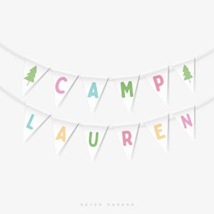 Op de afbeelding: Witte vlaggenlijn met de woorden "CAMP LAUREN" in kleurrijke letters. De vlaggenlijn bevat twee groene boomillustraties en is geregen aan een dun wit touw. De achtergrond is wit.