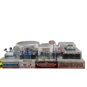 May include: A Command Force Chopper Patrol dual flight remote control helicopter toy set in original plastic packaging. The box features the text AH-6 LITTLE BIRD and DUAL FLIGHT REMOTE CONTROL HELICOPTER with a grey, black, and red color scheme.