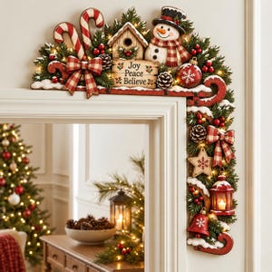 Könnte beinhalten: Eine Weihnachts-Türrahmendekoration mit einem Schneemann, einem Vogelhaus mit der Aufschrift Joy Peace Believe, Zuckerstangen, Tannenzapfen, roten Ornamenten, einer Laterne und einem Stern, verziert mit rot-karierten Schleifen.