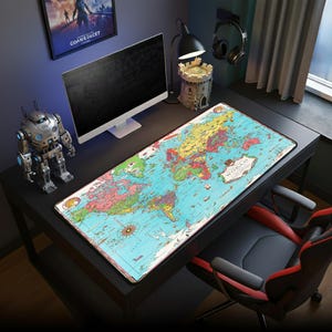 May include: A large rectangular desk mat featuring a vintage world map design. The mat is primarily blue with colorful continents and ocean details. The word "WORLD" is printed on the mat. The mat is on a black desk with a computer and other accessories.