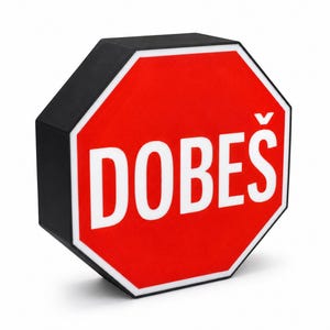 May include: An octagonal sign with a red face and a white border. The word DOBEŠ is printed in large white capital letters across the center. The sign has a thick black outer edge and is angled to show both the front face and the side profile.