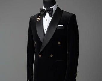 May include: A black velvet double-breasted tuxedo jacket with satin lapels, a white dress shirt, and a black bow tie. The jacket has gold buttons and a small gold emblem. The formal wear is displayed on a mannequin.