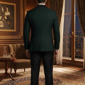 May include: A dark green suit jacket with a black lapel and black dress pants. The person is standing in a room with a painting, a chair, and a window with a view of city lights.