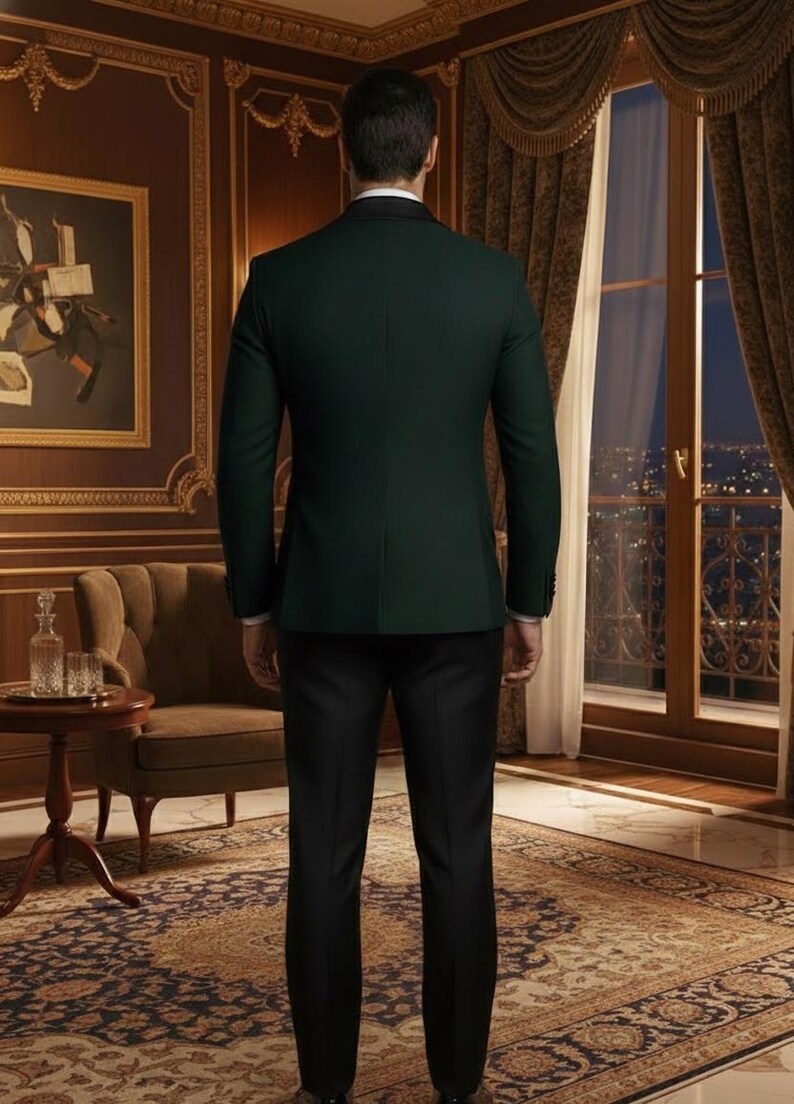 May include: A dark green suit jacket with a black lapel and black dress pants. The person is standing in a room with a painting, a chair, and a window with a view of city lights.